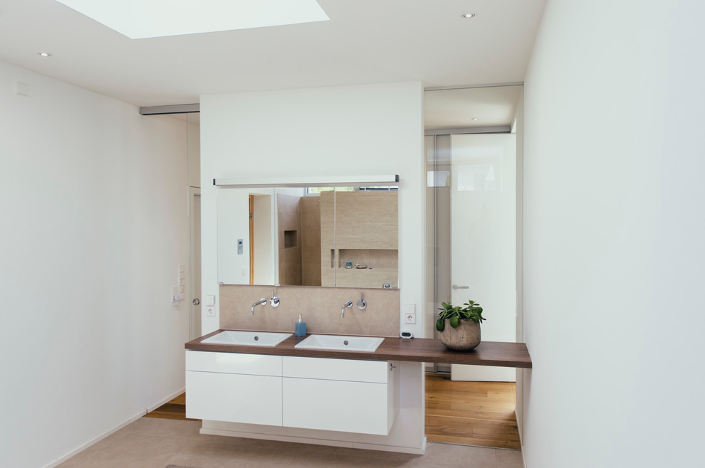 Источник вдохновения для домашнего уюта: ванная комната среднего размера в современном стиле с плоскими фасадами, белыми фасадами, бежевой плиткой, белыми стенами, накладной раковиной и столешницей из дерева