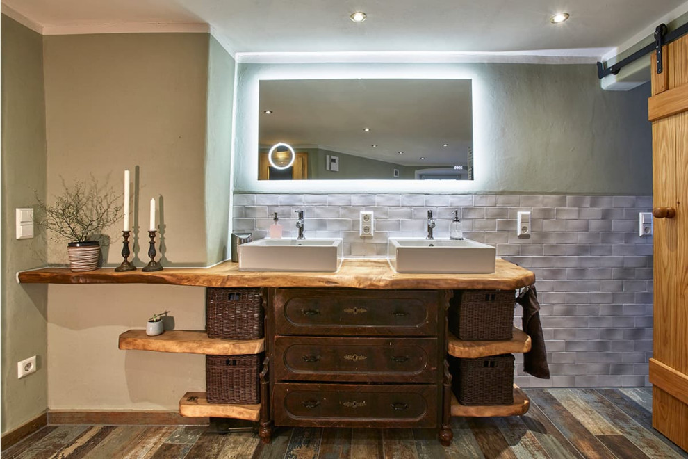 Inredning av ett rustikt stort beige beige en-suite badrum, med skåp i slitet trä, grå kakel, gröna väggar, målat trägolv, ett fristående handfat, träbänkskiva, flerfärgat golv och luckor med infälld panel