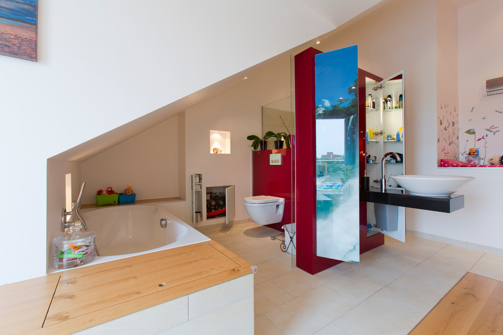 Idéer för funkis badrum, med släta luckor, röda skåp, ett platsbyggt badkar, en vägghängd toalettstol, vita väggar, kalkstensgolv och ett fristående handfat