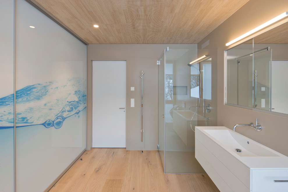Diseño de cuarto de baño actual con lavabo integrado, encimera de acrílico y ducha con puerta con bisagras