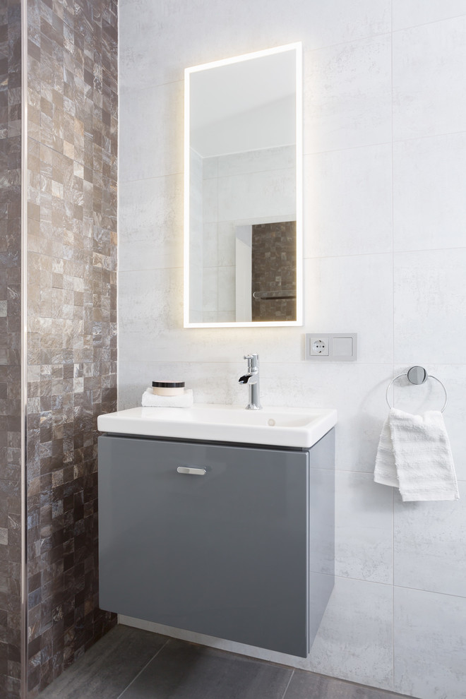 Example of a small trendy 3/4 gray tile and ceramic tile ceramic tile and gray floor bathroom design in Cologne with flat-panel cabinets, gray cabinets, a wall-mount toilet, gray walls and an integrated sink