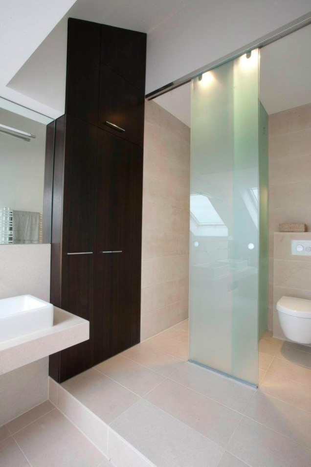 Cette image montre une douche en alcôve design en bois foncé avec un placard à porte plane, WC suspendus, un carrelage beige, une vasque, une baignoire posée, un mur blanc, un sol beige et une cabine de douche à porte coulissante.