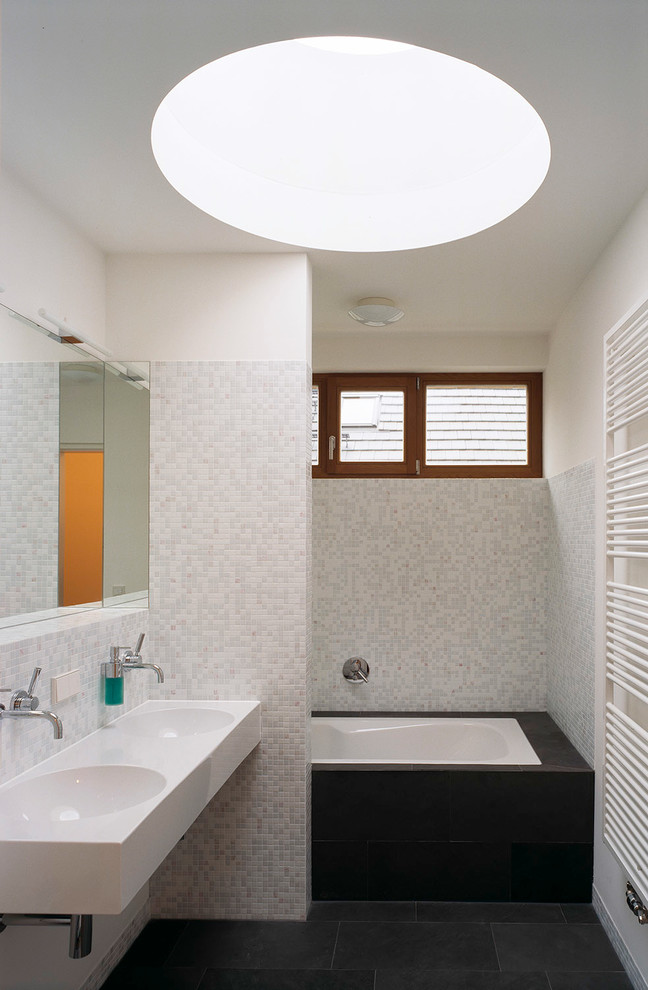 Aménagement d'une salle de bain contemporaine de taille moyenne avec une baignoire en alcôve, un combiné douche/baignoire, un carrelage gris, un carrelage blanc, mosaïque, un mur blanc et un lavabo intégré.