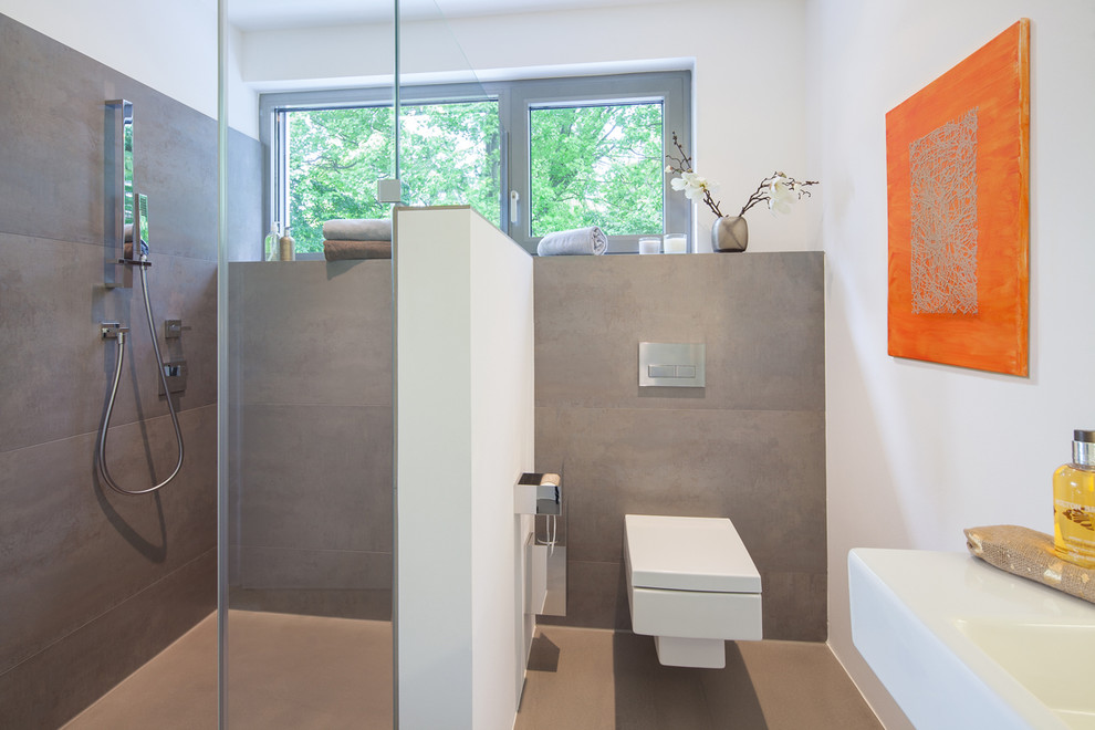 Imagen de cuarto de baño actual de tamaño medio con sanitario de pared, baldosas y/o azulejos grises, paredes blancas, ducha empotrada, losas de piedra, lavabo integrado y ventanas