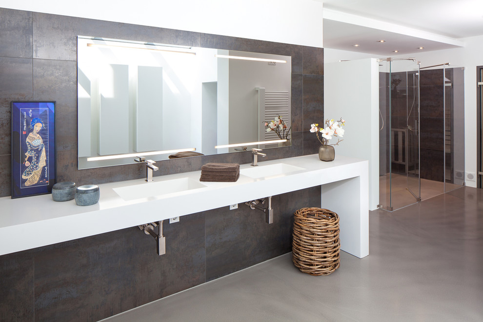 Foto di un'ampia stanza da bagno design con piastrelle grigie, pareti bianche, doccia alcova, piastrelle in pietra, lavabo integrato e top in superficie solida