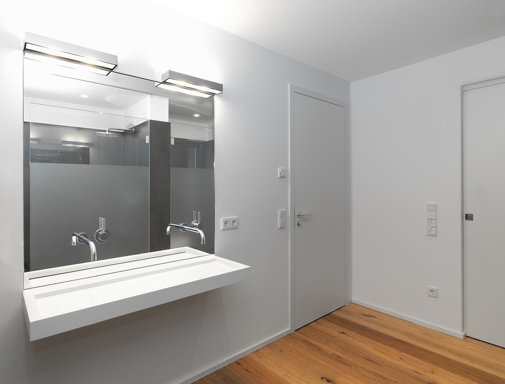 Exemple d'une grande salle de bain tendance avec un mur gris, un sol en bois brun et une grande vasque.
