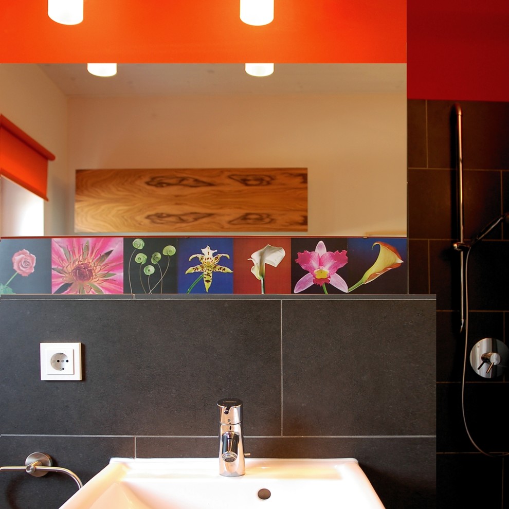 Inspiration pour une salle d'eau design en bois brun de taille moyenne avec un placard à porte vitrée, une baignoire indépendante, une douche à l'italienne, WC suspendus, un carrelage rouge, des carreaux de porcelaine, un mur noir, un sol en ardoise, un lavabo suspendu, un plan de toilette en surface solide, un sol noir et aucune cabine.