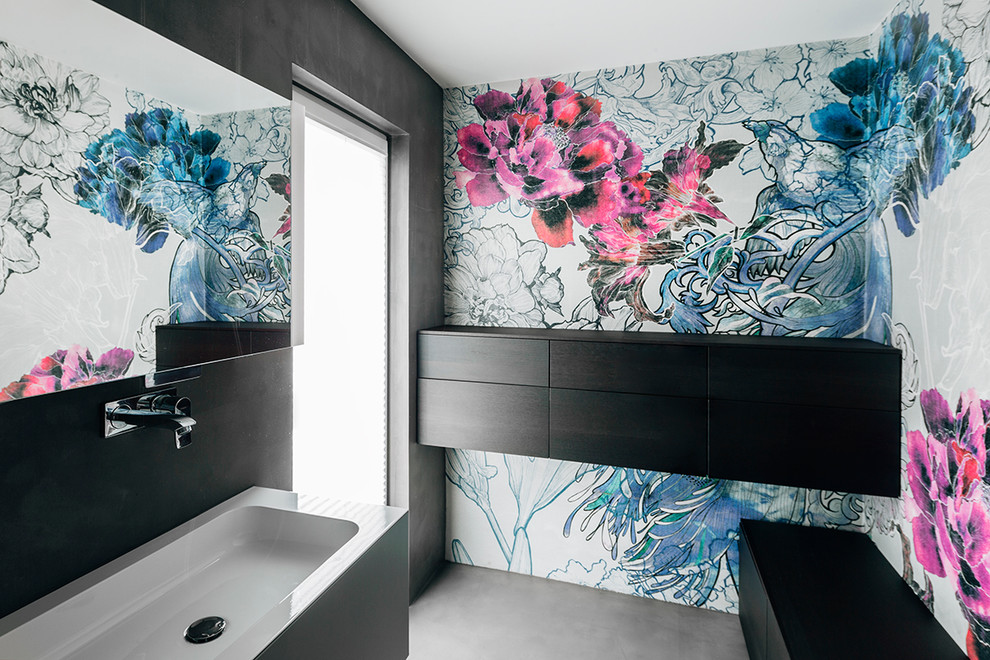Modernes Duschbad mit flächenbündigen Schrankfronten, Betonboden, schwarzen Schränken, bunten Wänden und integriertem Waschbecken in Sonstige