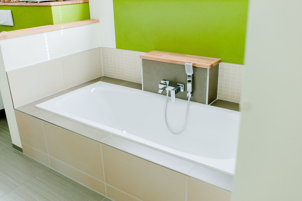 Idéer för att renovera ett mellanstort funkis brun brunt badrum, med vita skåp, ett platsbyggt badkar, en öppen dusch, en toalettstol med separat cisternkåpa, beige kakel, keramikplattor, gröna väggar, klinkergolv i porslin, ett fristående handfat, bänkskiva i akrylsten och grått golv