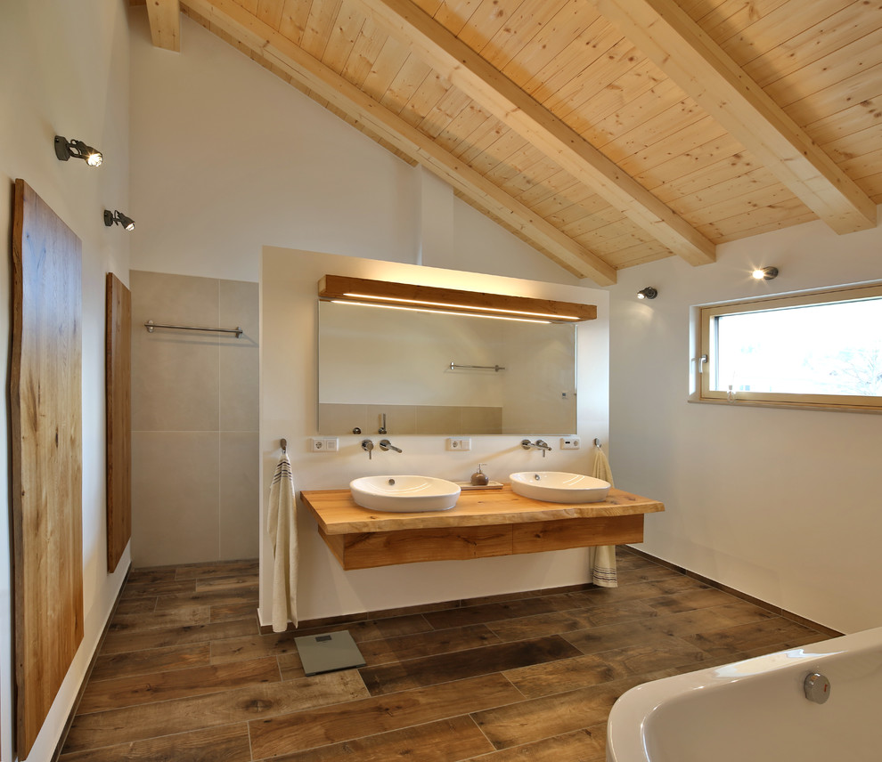 Bild på ett mellanstort funkis brun brunt badrum med dusch, med en öppen dusch, beige kakel, vita väggar, ett fristående handfat, träbänkskiva, med dusch som är öppen, skåp i mellenmörkt trä, ett fristående badkar och brunt golv