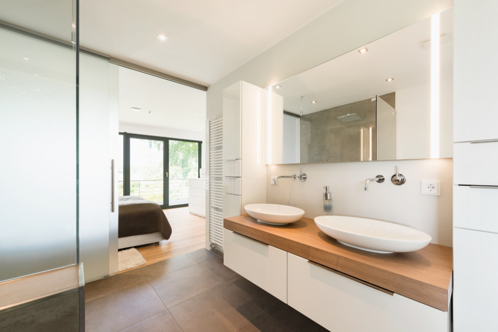 Design ideas for a medium sized contemporary ensuite bathroom in Bremen with white cabinets, a freestanding bath, a walk-in shower, a vessel sink, solid surface worktops, a sliding door, brown worktops, double sinks and a freestanding vanity unit.