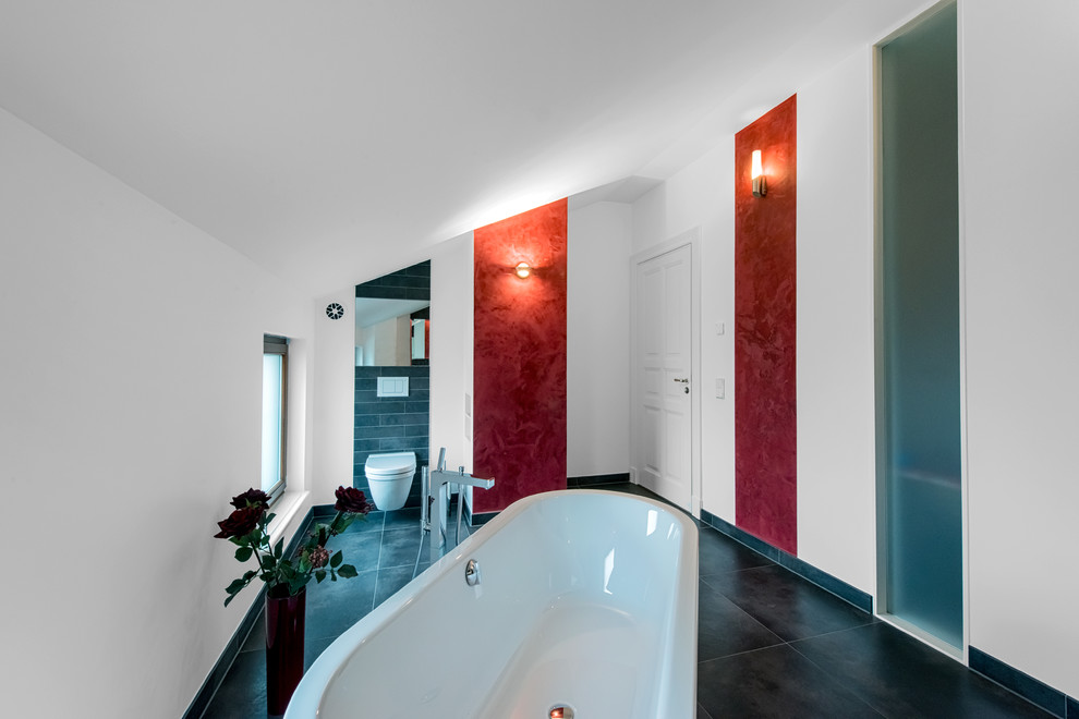 Inredning av ett modernt mellanstort badrum, med ett fristående badkar, en vägghängd toalettstol och vita väggar