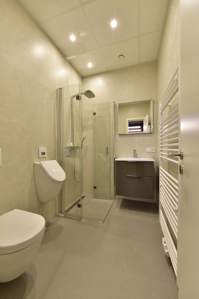 Mittelgroßes Modernes Duschbad mit flächenbündigen Schrankfronten, braunen Schränken, bodengleicher Dusche, Urinal, beiger Wandfarbe, integriertem Waschbecken, grauem Boden und Falttür-Duschabtrennung in Sonstige