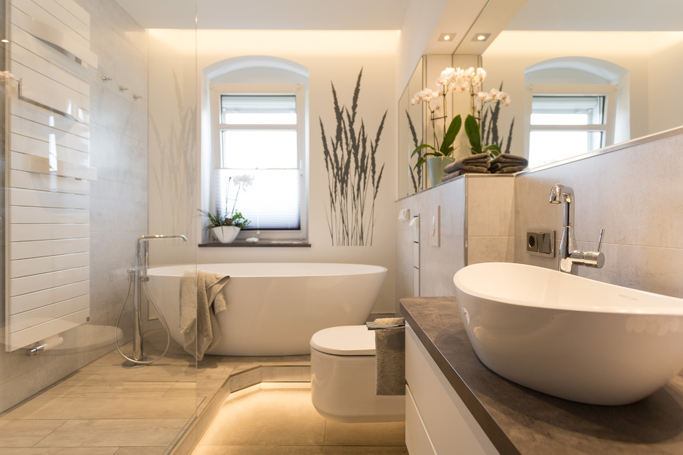 Свежая идея для дизайна: ванная комната среднего размера в современном стиле с плоскими фасадами, белыми фасадами, отдельно стоящей ванной, инсталляцией, бежевой плиткой, белыми стенами, душевой кабиной, настольной раковиной, бежевым полом и коричневой столешницей - отличное фото интерьера
