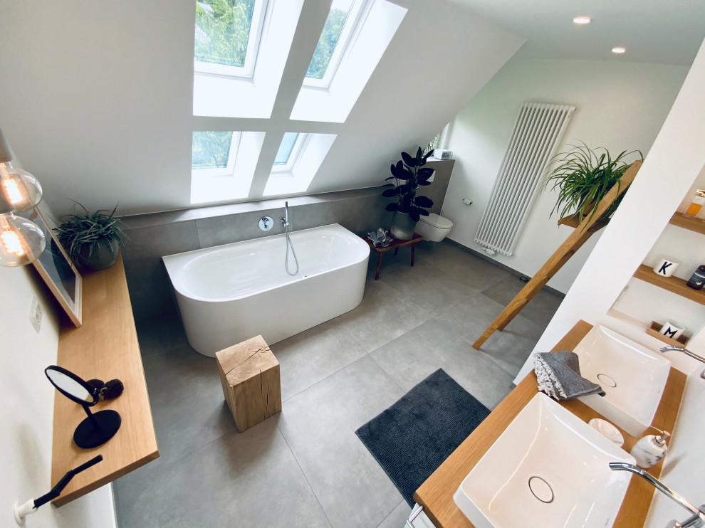 Стильный дизайн: большая ванная комната в современном стиле с белыми фасадами, отдельно стоящей ванной, открытым душем, инсталляцией, белыми стенами, бетонным полом, настольной раковиной, серым полом, открытым душем, тумбой под две раковины и подвесной тумбой - последний тренд