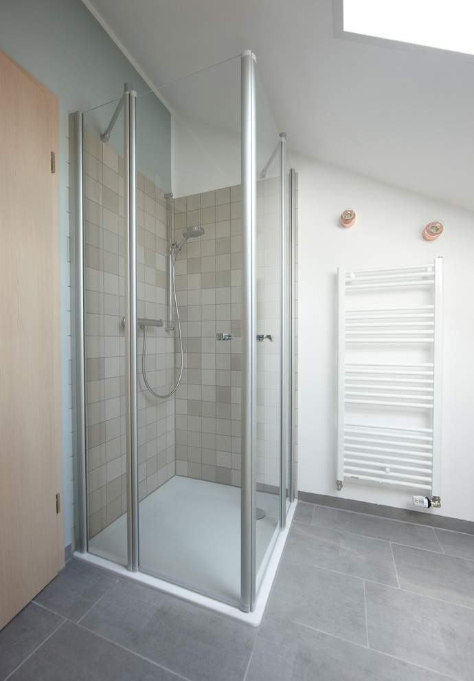 Skandinavisk inredning av ett litet badrum med dusch, med öppna hyllor, skåp i ljust trä, en kantlös dusch, en vägghängd toalettstol, beige kakel, porslinskakel, flerfärgade väggar, ett avlångt handfat, träbänkskiva och betonggolv