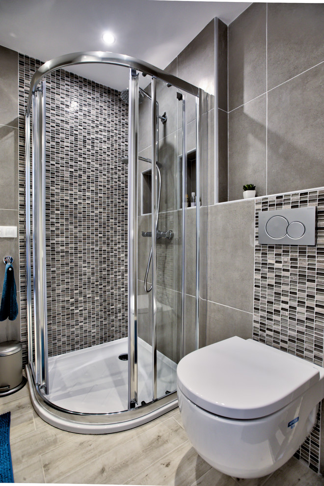 Small contemporary shower room bathroom with white cabinets, a corner shower, a wall mounted toilet, beige tiles, ceramic tiles, beige walls, ceramic flooring, an integrated sink, beige floors and a sliding door.