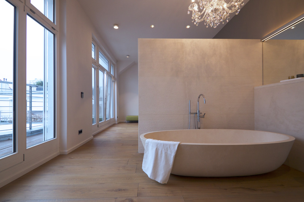 Inspiration för stora moderna en-suite badrum, med ett fristående badkar, en kantlös dusch, en vägghängd toalettstol, beige kakel, grå väggar, mellanmörkt trägolv, ett väggmonterat handfat, brunt golv och dusch med gångjärnsdörr
