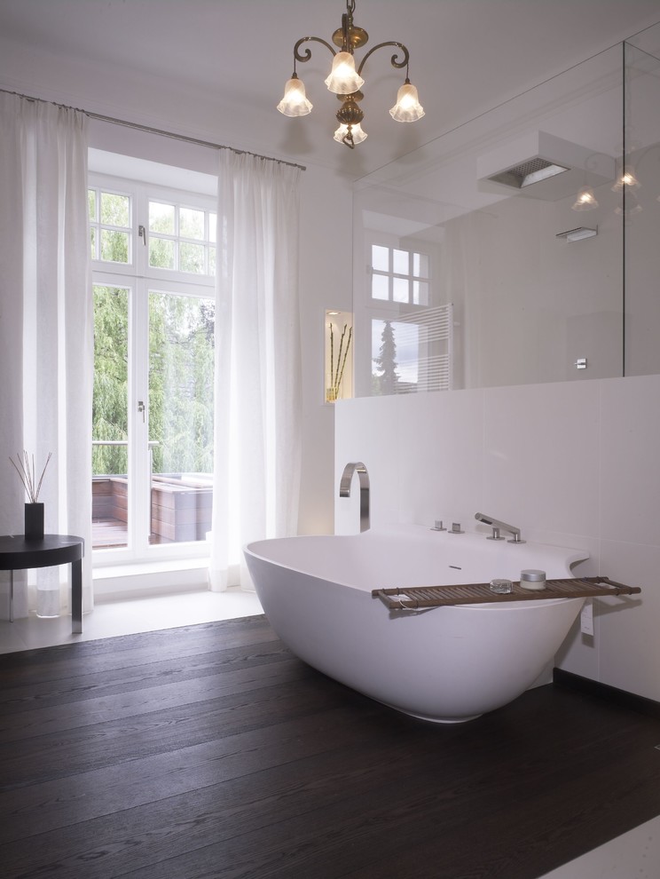 Exempel på ett mellanstort modernt brun brunt badrum, med skåp i mörkt trä, ett fristående badkar, en kantlös dusch, en vägghängd toalettstol, beige kakel, kakelplattor, beige väggar, mörkt trägolv, ett fristående handfat, bänkskiva i akrylsten, brunt golv och med dusch som är öppen