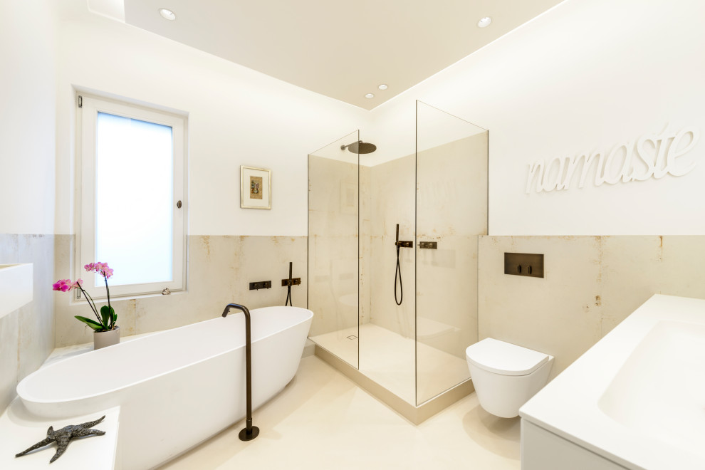 Idéer för mellanstora shabby chic-inspirerade vitt badrum, med ett fristående badkar, en vägghängd toalettstol, beige kakel, beiget golv, släta luckor, vita skåp, en öppen dusch, keramikplattor, beige väggar, ett integrerad handfat, bänkskiva i akrylsten och med dusch som är öppen