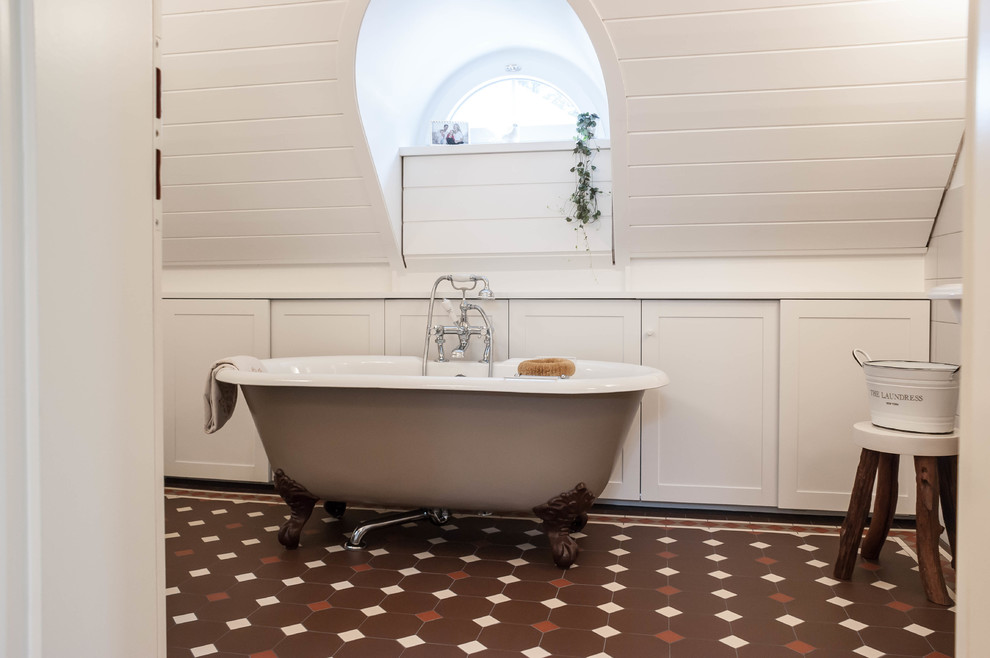 Ispirazione per una stanza da bagno con doccia vittoriana con ante bianche, vasca freestanding, pareti bianche, pavimento in cementine e pavimento marrone