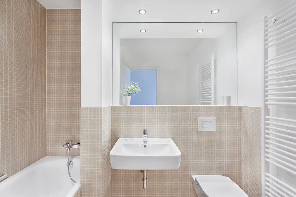 Esempio di una piccola stanza da bagno contemporanea con lavabo sospeso, vasca ad alcova, piastrelle beige, piastrelle a mosaico, pareti beige, vasca/doccia e WC sospeso
