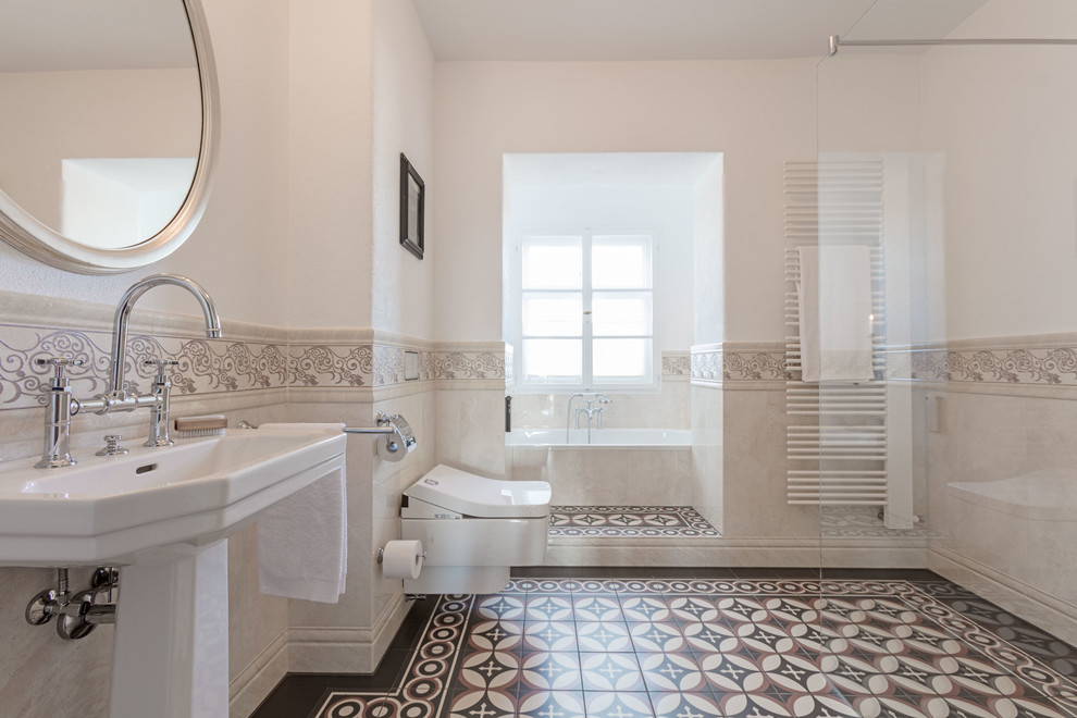 Inspiration för ett stort vintage en-suite badrum, med ett platsbyggt badkar, en kantlös dusch, en vägghängd toalettstol, beige kakel, beige väggar, ett piedestal handfat, med dusch som är öppen, cementkakel, flerfärgat golv och klinkergolv i keramik