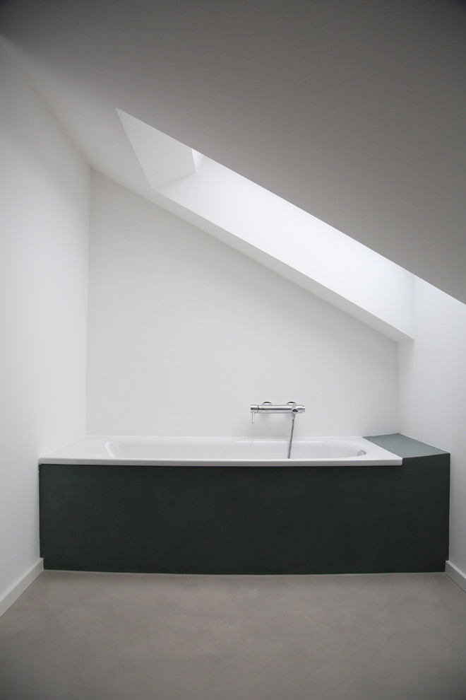 Modelo de cuarto de baño actual con paredes blancas y suelo de cemento