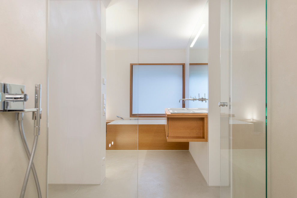 Geräumiges Modernes Badezimmer mit Wandwaschbecken, hellbraunen Holzschränken, Eckbadewanne, bodengleicher Dusche und beiger Wandfarbe in Stuttgart