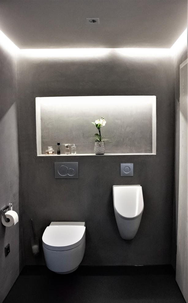 Große Moderne Gästetoilette mit flächenbündigen Schrankfronten, braunen Schränken, Wandtoilette, schwarzen Fliesen, schwarzer Wandfarbe, integriertem Waschbecken, Mineralwerkstoff-Waschtisch, schwarzem Boden und brauner Waschtischplatte in Stuttgart