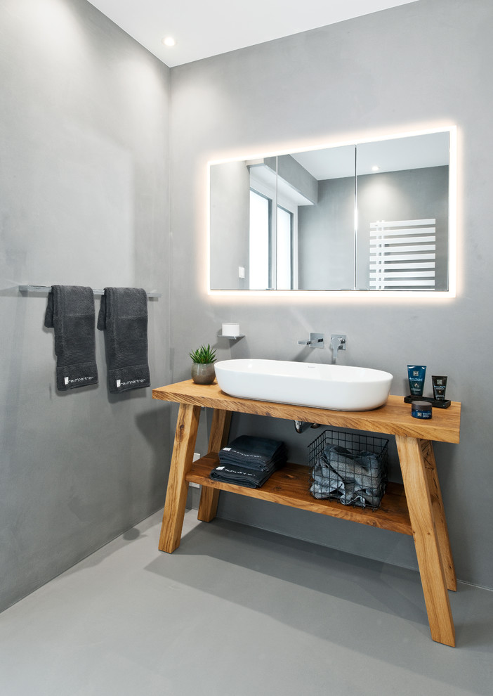 Foto de cuarto de baño contemporáneo con puertas de armario de madera oscura, paredes grises, lavabo sobreencimera, encimera de madera y suelo gris