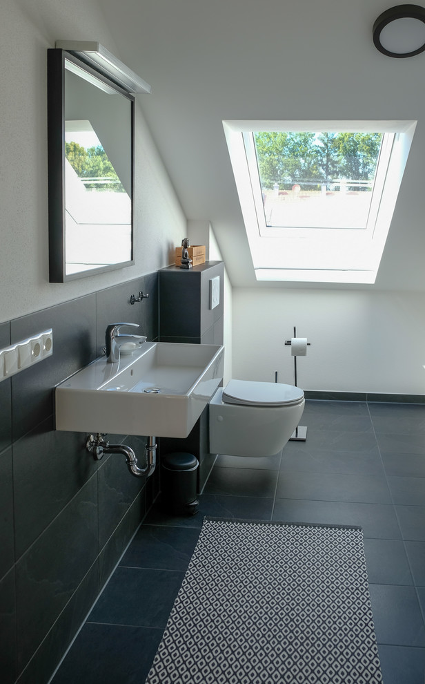 Inspiration för ett mellanstort funkis en-suite badrum, med en vägghängd toalettstol, keramikplattor, klinkergolv i porslin, ett väggmonterat handfat och svart golv