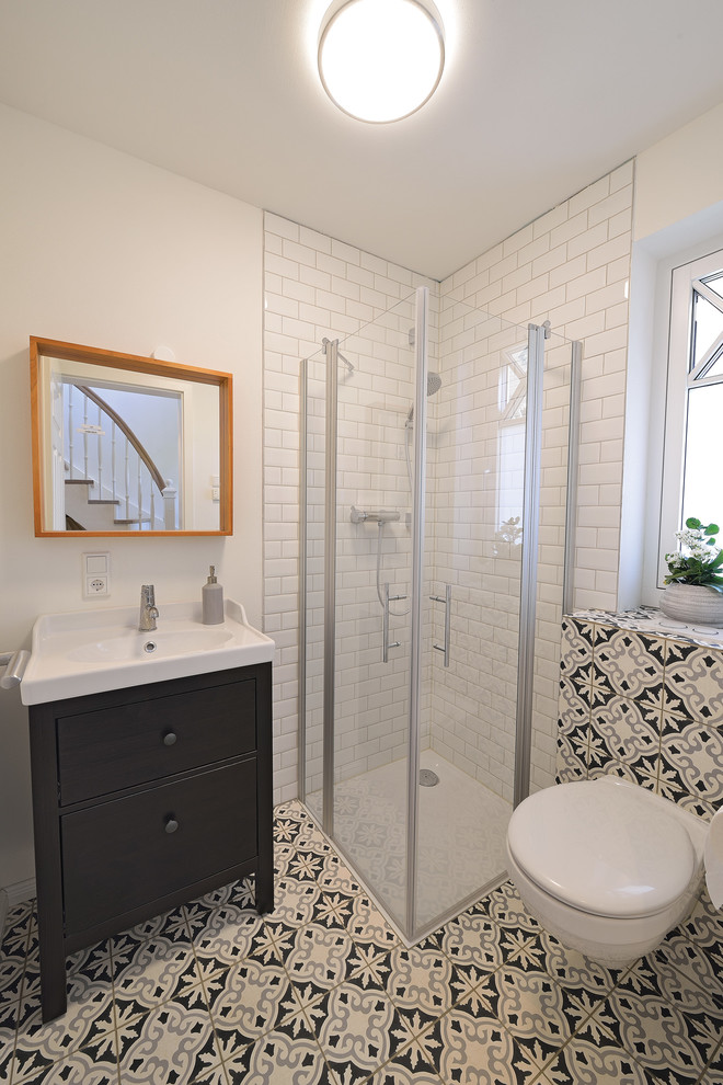 Cette photo montre une petite salle de bain scandinave en bois foncé avec un placard à porte plane, un carrelage multicolore, des carreaux de porcelaine, un mur noir, sol en béton ciré, un plan vasque et une douche à l'italienne.