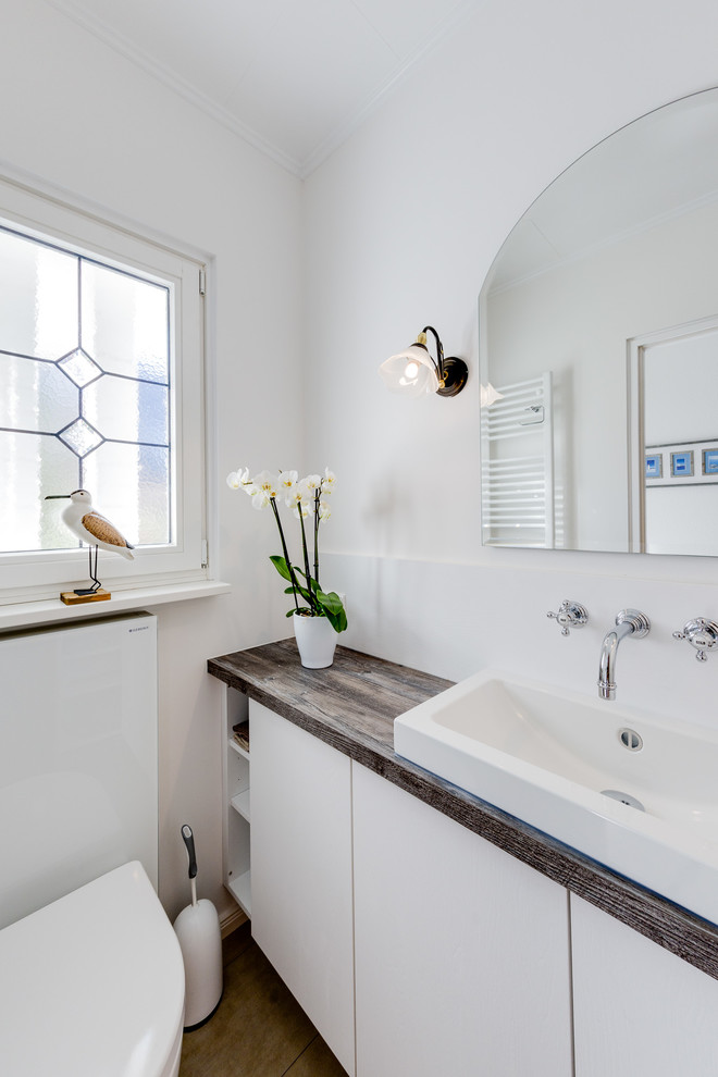 Aménagement d'une petite salle de bain contemporaine avec un placard à porte plane, des portes de placard blanches, WC suspendus, un carrelage blanc, des carreaux de miroir, un mur blanc, un sol en carrelage de céramique, une vasque, un plan de toilette en surface solide et un sol beige.