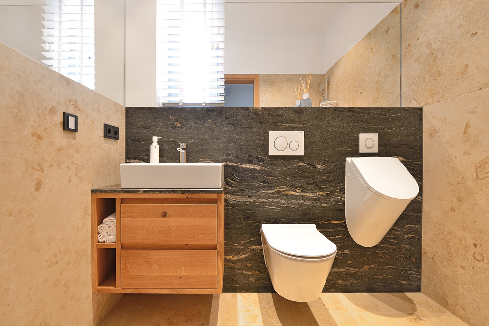 Пример оригинального дизайна: ванная комната среднего размера в современном стиле с фасадами с выступающей филенкой, светлыми деревянными фасадами, душем без бортиков, раздельным унитазом, бежевой плиткой, каменной плиткой, полом из известняка, душевой кабиной, настольной раковиной, столешницей из дерева, бежевым полом, открытым душем и черной столешницей