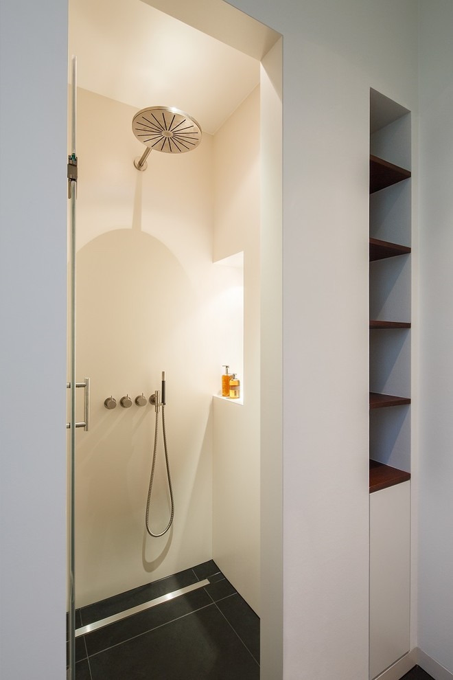 Inredning av ett modernt mellanstort badrum med dusch, med släta luckor, vita skåp, ett hörnbadkar, en kantlös dusch, en toalettstol med separat cisternkåpa, vit kakel, marmorkakel, vita väggar, kalkstensgolv, ett fristående handfat, träbänkskiva, grått golv och med dusch som är öppen