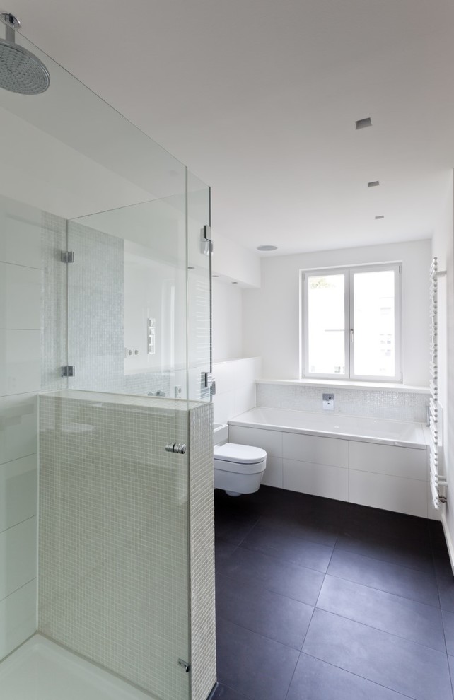 This is an example of a large contemporary shower room bathroom in Cologne with a built-in bath, a built-in shower, a wall mounted toilet, white tiles, mosaic tiles, white walls and ceramic flooring.