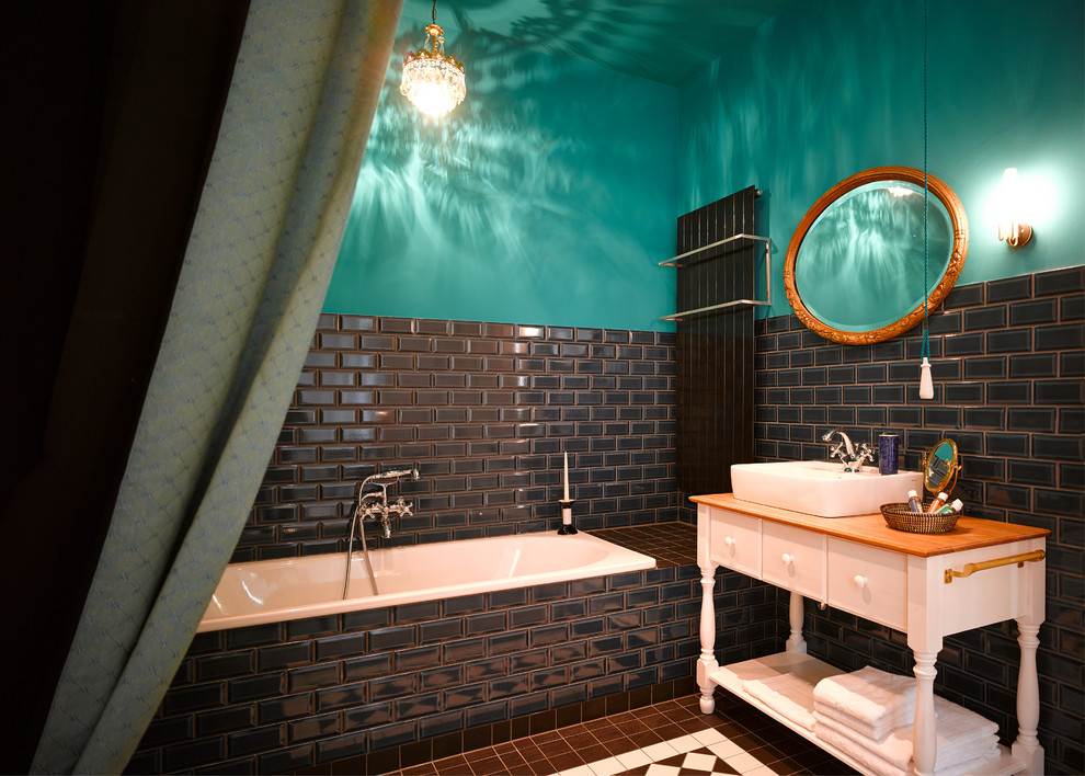 На фото: ванная комната среднего размера в стиле фьюжн с настольной раковиной, белыми фасадами, накладной ванной, черной плиткой, плиткой кабанчик, синими стенами, столешницей из дерева, коричневой столешницей и плоскими фасадами