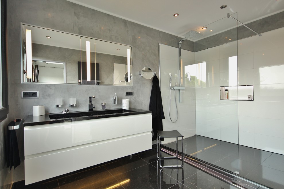 Idée de décoration pour une salle de bain design de taille moyenne avec un placard à porte plane, des portes de placard blanches, une douche à l'italienne, un mur gris et un lavabo intégré.