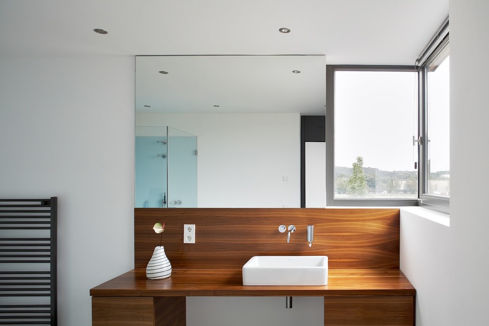 Inspiration för mellanstora moderna badrum, med ett fristående handfat, träbänkskiva, släta luckor, skåp i mellenmörkt trä och vita väggar
