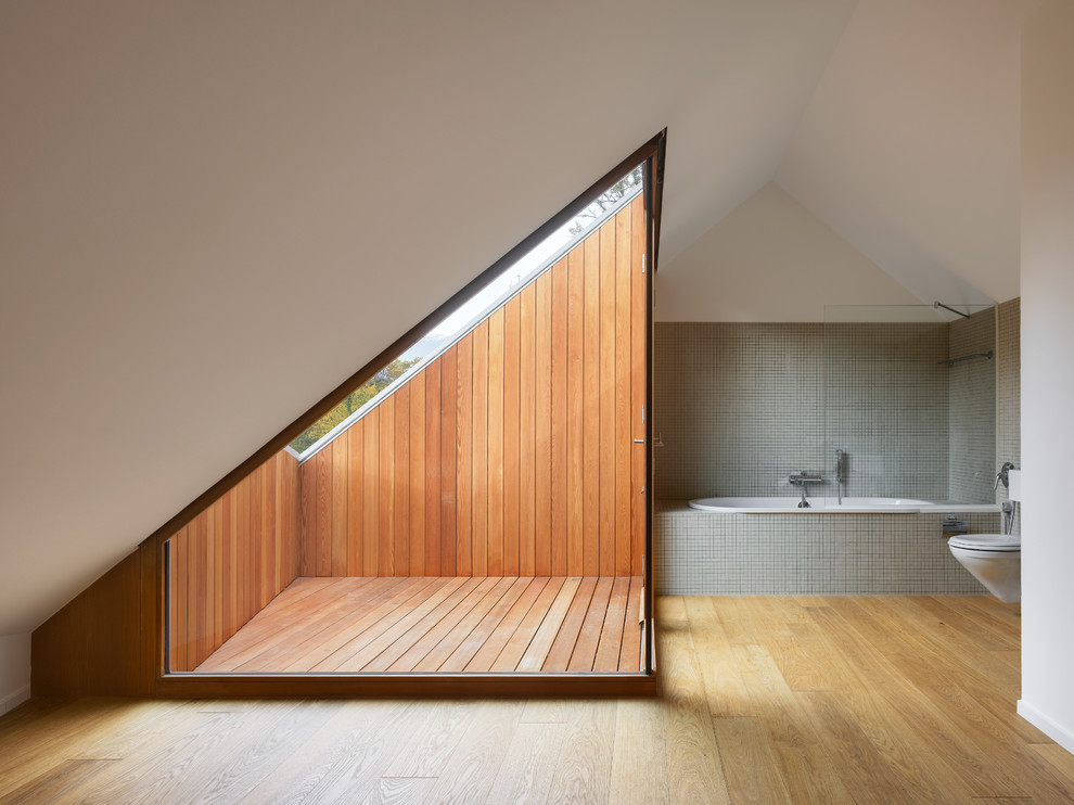 На фото: ванная комната среднего размера в стиле кантри с ванной в нише, душем над ванной, инсталляцией, серой плиткой, плиткой мозаикой, белыми стенами и паркетным полом среднего тона с