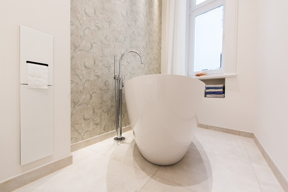 Idéer för mellanstora funkis en-suite badrum, med släta luckor, vita skåp, ett fristående badkar, en kantlös dusch, en vägghängd toalettstol, grå kakel, vita väggar, ett integrerad handfat, grått golv och dusch med gångjärnsdörr