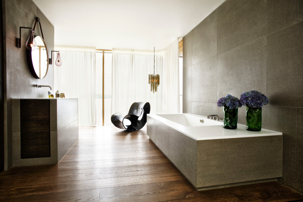 Foto di una stanza da bagno padronale contemporanea con vasca da incasso, piastrelle grigie, pavimento in legno massello medio e pareti grigie