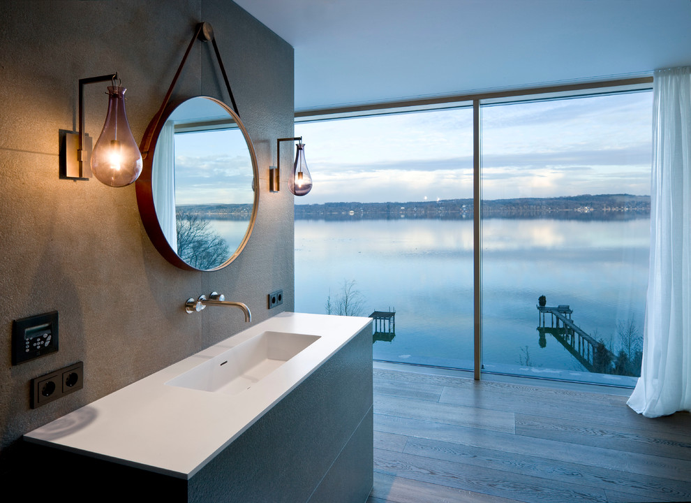 Esempio di una stanza da bagno contemporanea con piastrelle grigie, lastra di pietra, pareti grigie, pavimento in legno massello medio, lavabo integrato e top in superficie solida