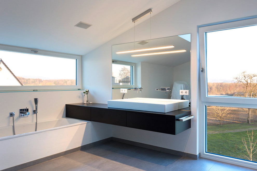 Imagen de cuarto de baño moderno, grande, con lavabo sobreencimera, armarios con paneles lisos, puertas de armario negras, bañera encastrada y paredes blancas