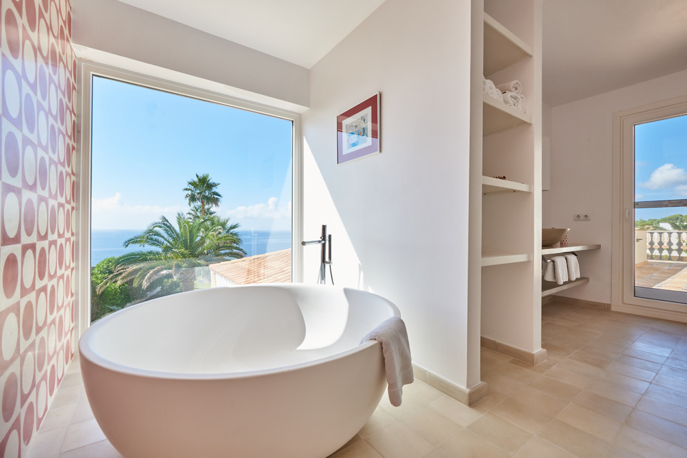 Foto på ett maritimt badrum, med öppna hyllor, ett fristående badkar, vita väggar, klinkergolv i keramik, ett fristående handfat och beiget golv