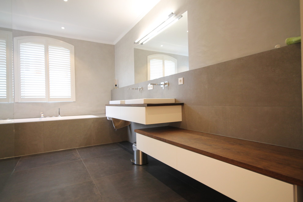 На фото: ванная комната в классическом стиле с белыми фасадами, накладной ванной, серой плиткой, серыми стенами, душевой кабиной и настольной раковиной