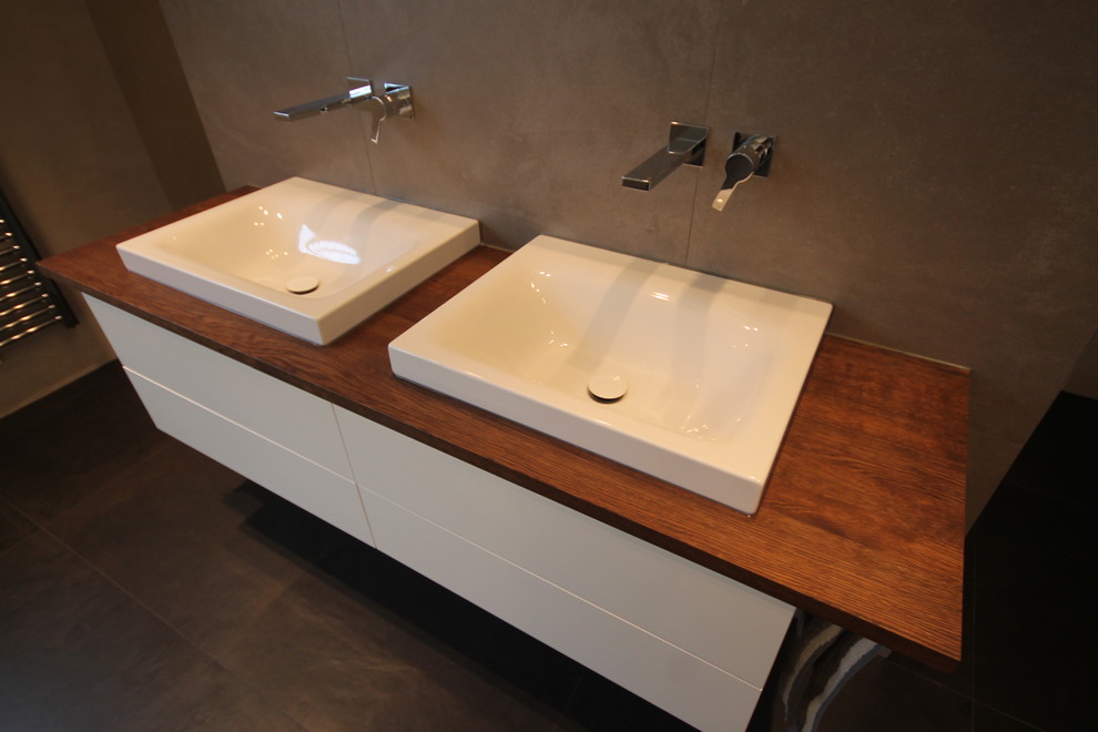 Diseño de cuarto de baño tradicional con puertas de armario blancas, bañera encastrada, baldosas y/o azulejos grises, paredes grises, aseo y ducha y lavabo sobreencimera