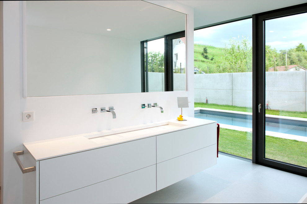 Idéer för ett mellanstort modernt badrum, med släta luckor, vita skåp, vita väggar, betonggolv och ett avlångt handfat
