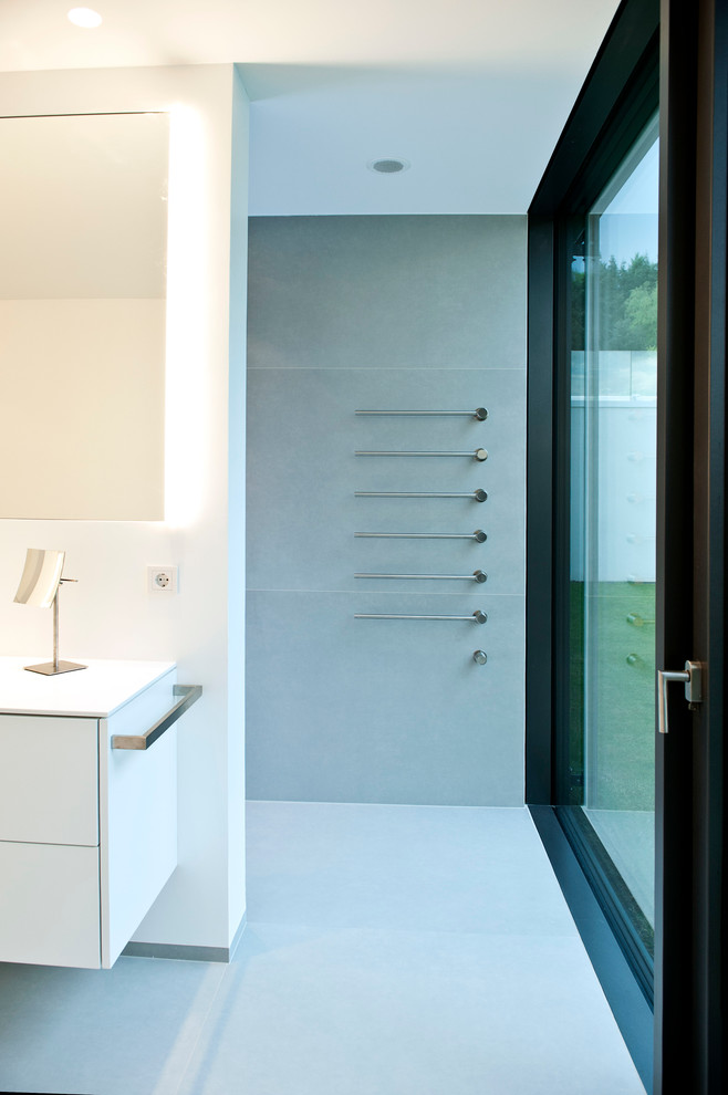 Modelo de cuarto de baño moderno grande con armarios con paneles lisos, puertas de armario blancas, baldosas y/o azulejos grises, losas de piedra y suelo de cemento
